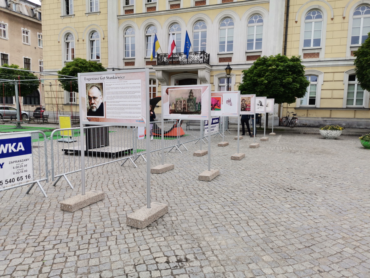 na foto rynek przed ratuszem we Wschowie. Na pierwszym planie stojaki z pracami